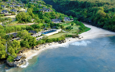 Luxury villas tucked away on a green hill sloping towards the ocean.